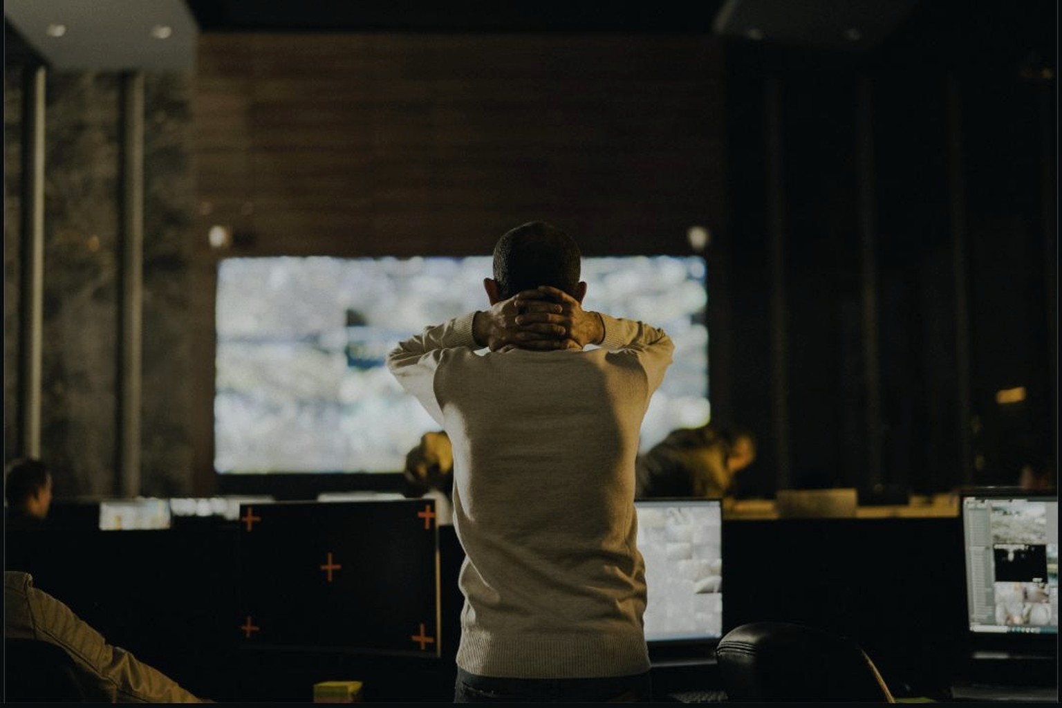 Operator in front of a large screen in a dark control room