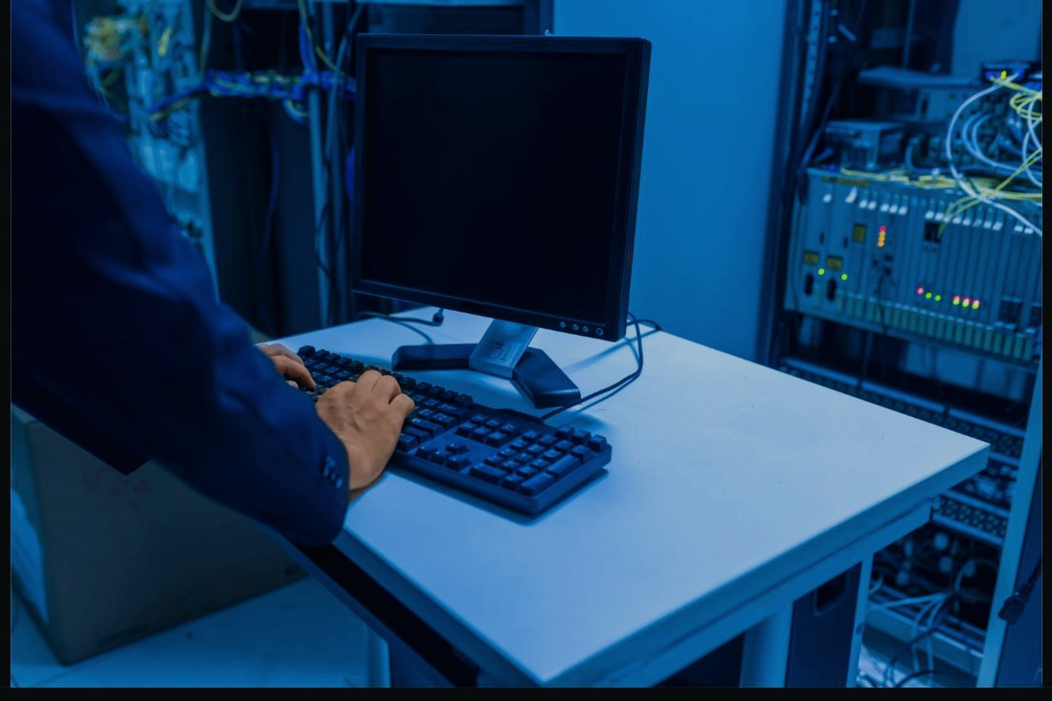 Person working at a computer next to network equipment
